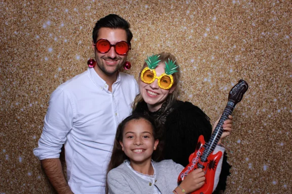 Familie mit lustigen Brillen vor der Fotobox mit goldenem Hintergrund in Königsbrunn.