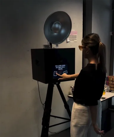 Frau von hinten, die die Fotofunktion der Fotobox auf einer Firmenfeier in Landsberg auslöst.
